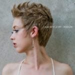 Profile of a person with short, styled blond hair and dramatic eye makeup.