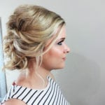 Profile view of a woman with styled blonde hair in an updo.