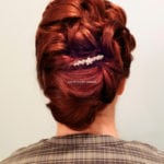 Intricate braided updo with a decorative hairpin.
