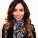 A woman with long wavy hair wearing a leopard print scarf and black top.