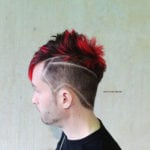 Side profile of a man with a red mohawk and shaved lines.