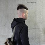 Side profile of a person with a unique high fade haircut wearing a black hoodie.