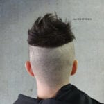 A person with a unique haircut featuring a shaved lower head and longer hair on top.