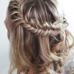 A close-up of a blonde hairstyle with a braided crown and loose curls.