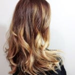 Wavy ombre hairstyle with brown roots and blonde tips.