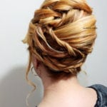 Intricately styled blonde updo with loose curls.