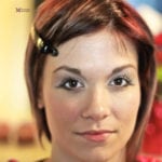 A close-up portrait of a woman with a hairpin in her brown hair.