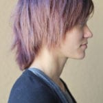 Profile of a person with layered purple hair wearing a dark top.