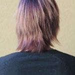 Back view of a person with layered, shoulder-length hair dyed purple.