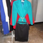 A turquoise blazer paired with a black skirt on a hanger.