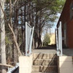 A set of concrete stairs with metal railings outside between trees and buildings.