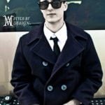 A man in a dark trench coat and sunglasses.