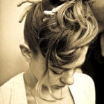 A sepia-toned photo of a woman with an elaborate updo hairstyle looking down.