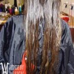 Long wet hair draped over a black cape during a haircut.