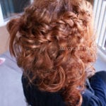 Curly red hair styled with braids on top.