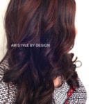 A photo of long, wavy dark hair with reddish highlights.