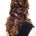 Long, wavy brown hair styled with curls on a person wearing a black top.
