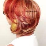 Short layered haircut with vibrant red and yellow colors.