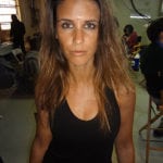 A woman with long brown hair wearing a black sleeveless top.
