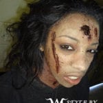 A person with realistic zombie makeup and fake blood on their face.