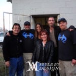Group of six people posing outdoors, some wearing matching black hoodies.