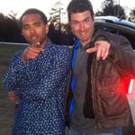 Two men posing outdoors, pointing at the camera.