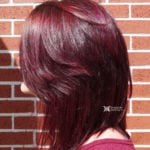 A woman with shiny burgundy hair styled in a smooth, layered bob.