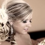 A bride with elegant hairstyle and veil looking down.
