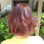 Back view of a person with short, reddish hair outdoors.