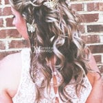 A girl with long curly hair styled with a butterfly clip.