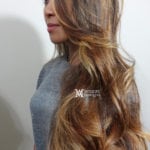 Side view of a woman with long wavy hair and a gray sweater.