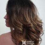 Profile of a woman with long, wavy brown hair.