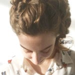 A woman with braided hair looking down.