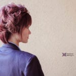 A woman with short, styled purple hair wearing a purple jacket.