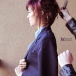 Profile of a woman with purple hair wearing a blue blazer.
