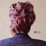Back view of a person with styled pinkish-purple hair.
