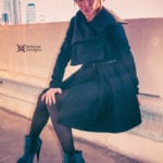 A woman in a black outfit sitting on steps.