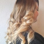 Blonde hair styled in loose curls on a woman.