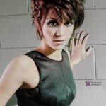 A woman with short hair posing against a wall.