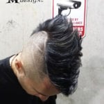 A man with a unique hairstyle featuring shaved sides and voluminous black hair on top.