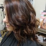 Side view of a woman with styled, wavy brown hair.
