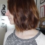 Profile of a woman with shoulder-length wavy brown hair in a casual setting.