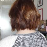 Back view of a person with short, wavy brown hair.