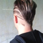 Rear view of a hairstyle with shaved curved lines and longer top hair.