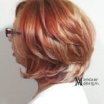 Side view of a woman with layered reddish-brown hair and glasses.