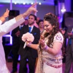 A bride holding a bouquet and smiling during a wedding celebration.