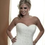 A smiling bride in a strapless white wedding dress.