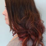 Profile of a woman with wavy brown hair and red highlights.