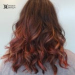 Shoulder-length wavy hair with reddish highlights.