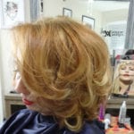 Side view of a woman with styled blonde hair in a salon.
